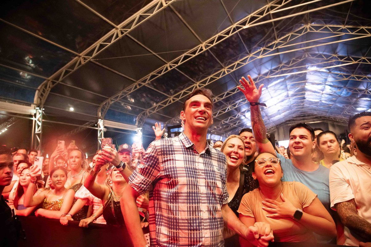 Público com os braços erguidos sob a tenda