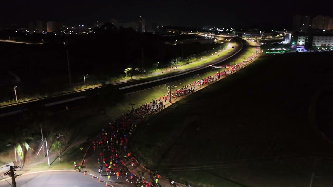 Fila de corredores iluminada percorrendo a avenida à noite